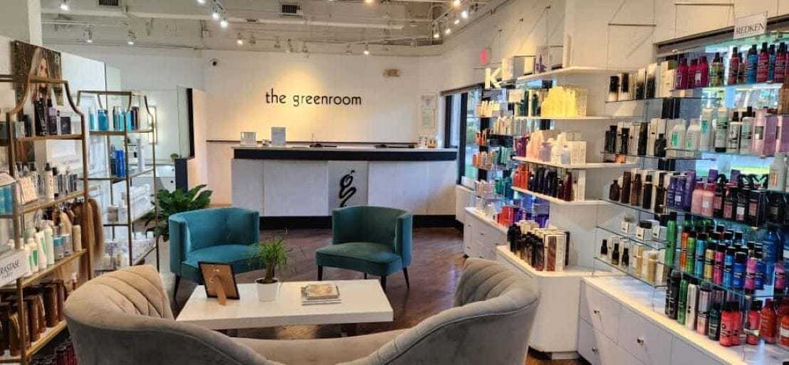 Salon interior with product displays, seating area, and "the greenroom" sign.